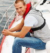 Happy young man wearing a life jacket in a sail boat at sea