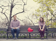 Sad teens sitting at the bench at the park