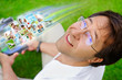 Adult man sitting on grass in park and using social media to loo