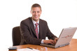 Businessman sitting on his desk with laptop and smiles