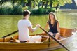 Couple in rowing boat, man rowing, smiling at each other"